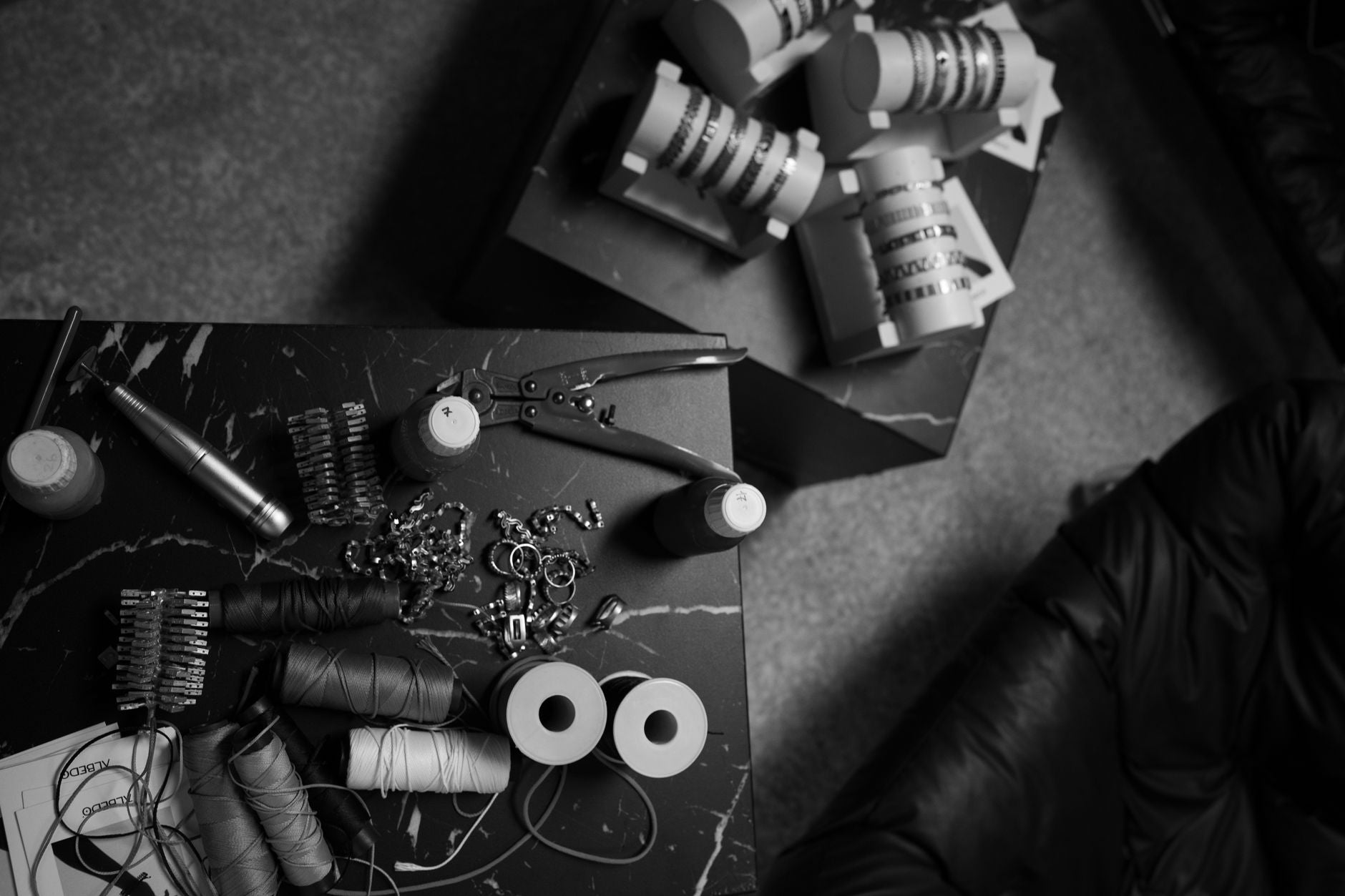 Aerial view of sewing accessories and tools on a black marble table in monochrome.