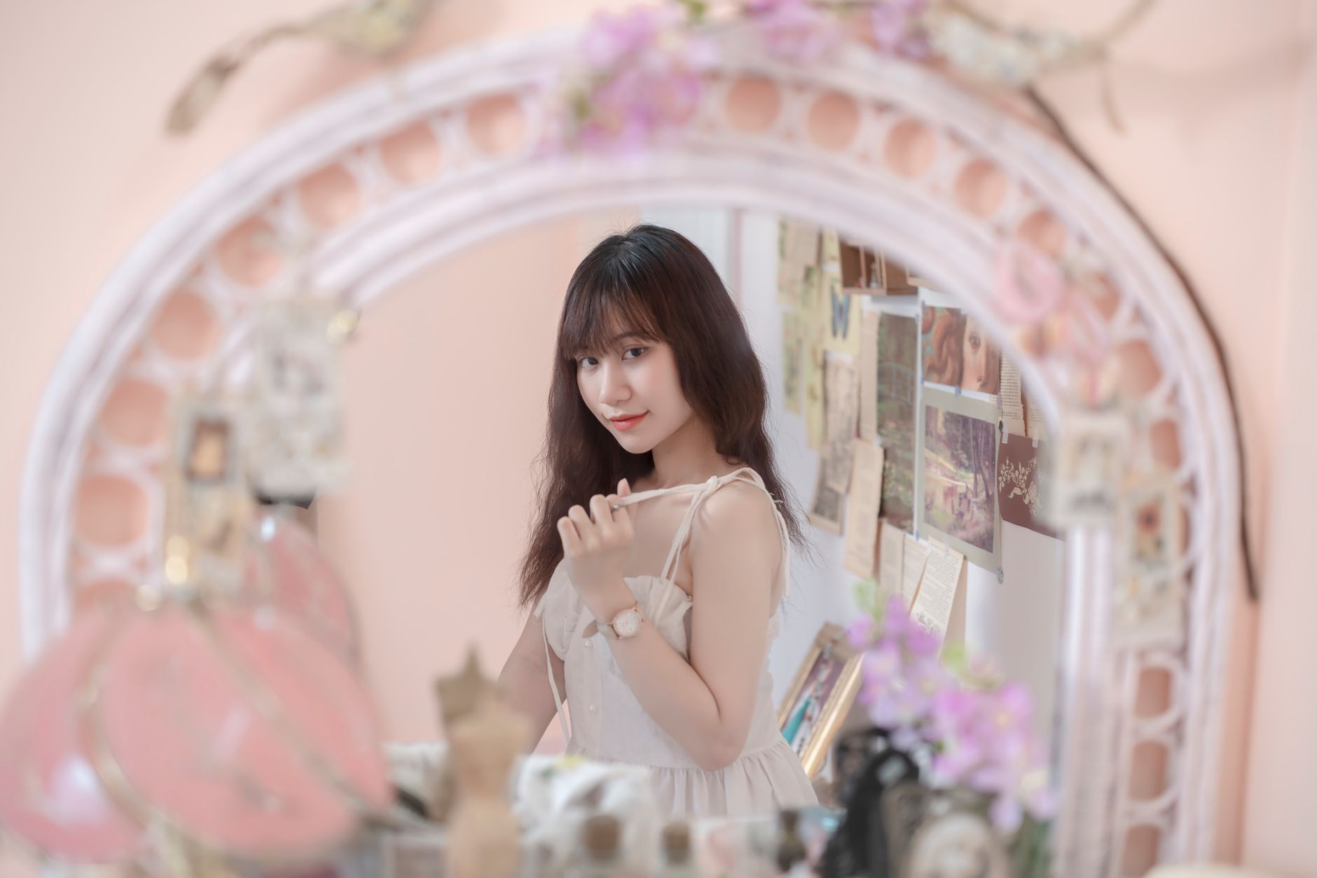 Young woman in white dress posing gracefully in a vintage mirror reflection.