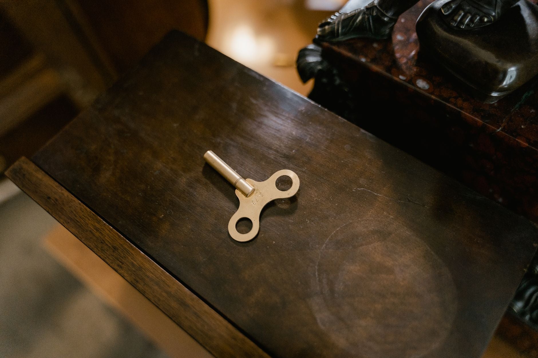 A vintage clockwork key placed on a polished wooden surface, showcasing retro charm.