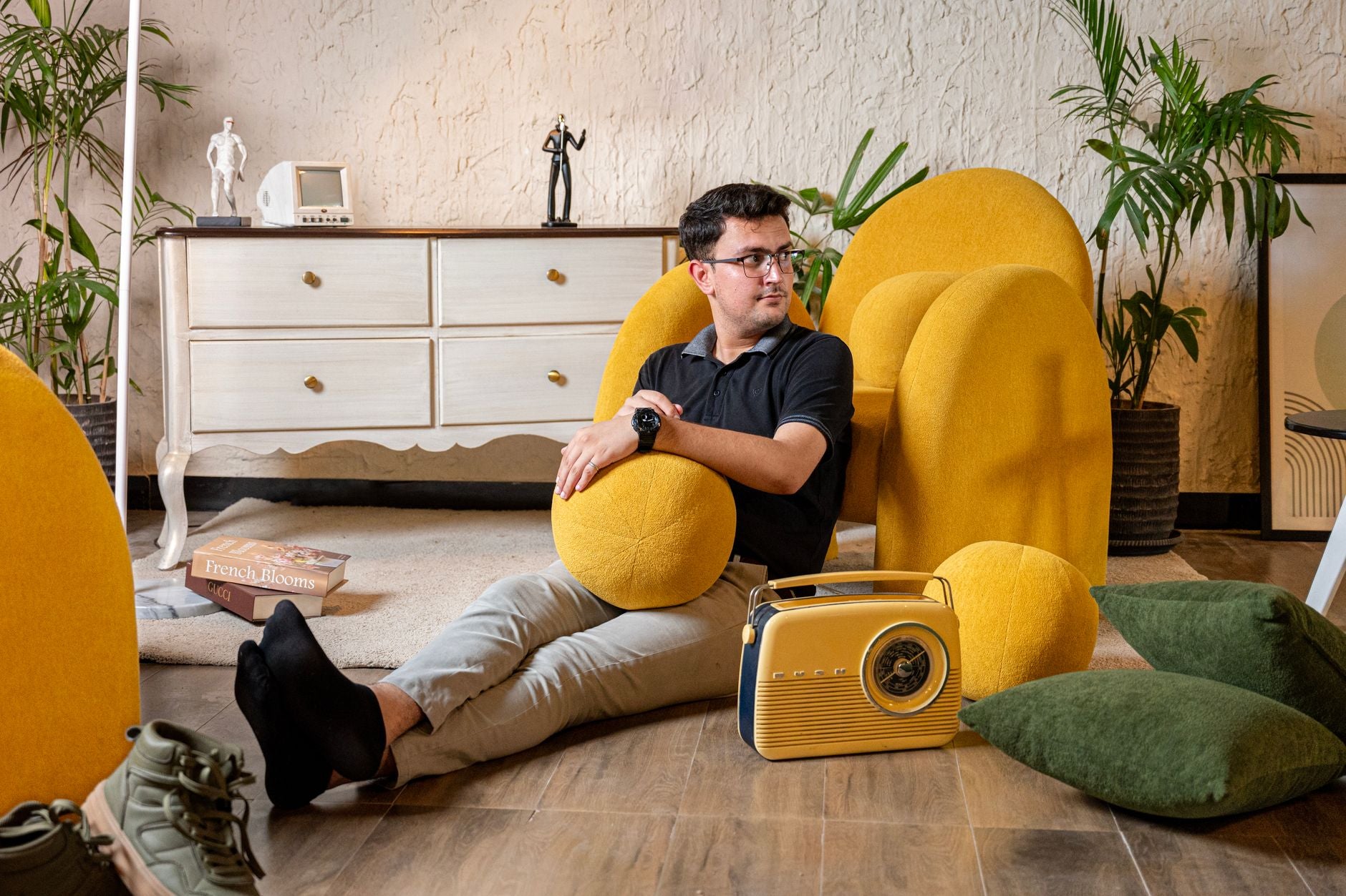 Man relaxing in a stylish living room with a vintage radio and yellow furniture, embodying a cozy modern vibe.