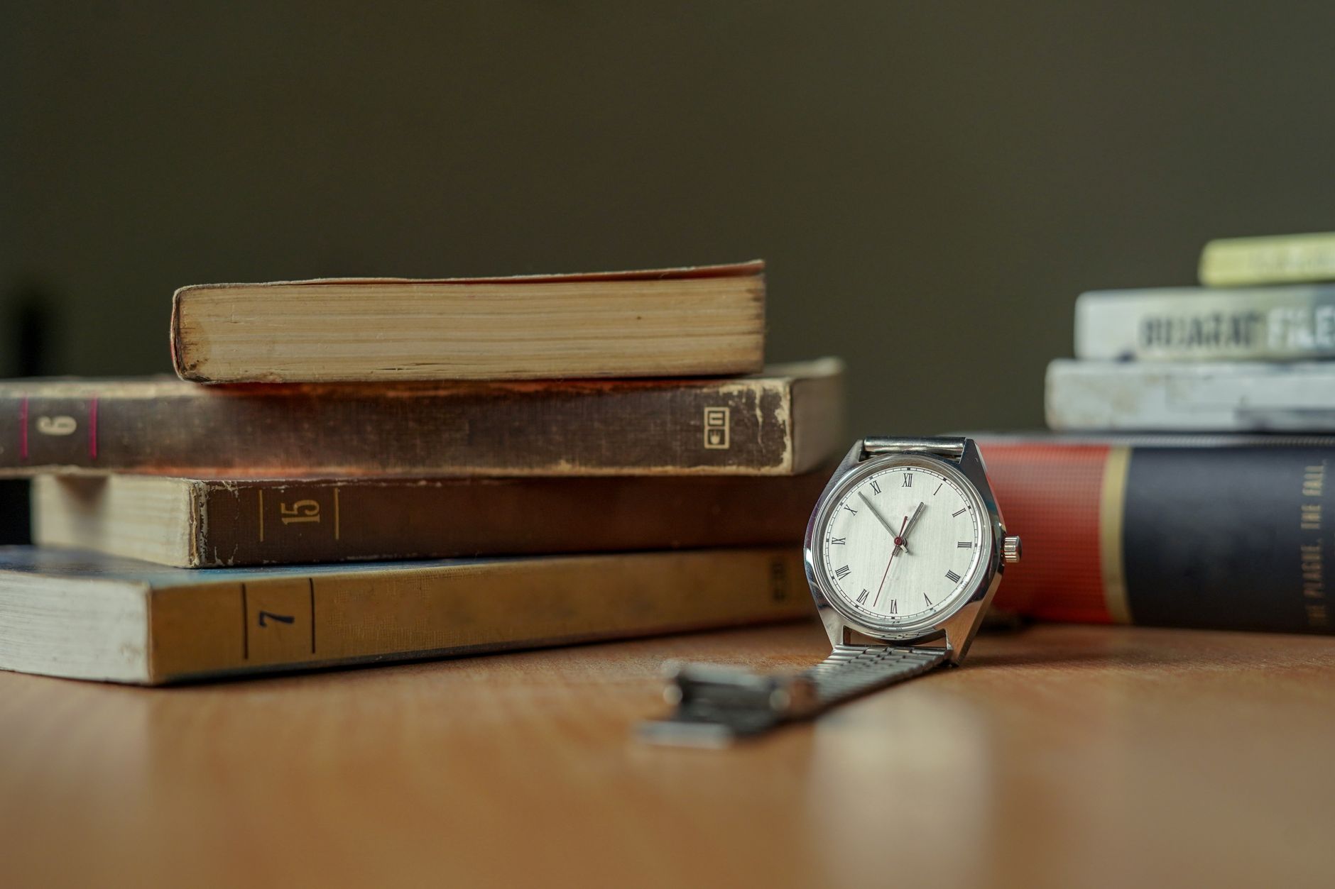 A classic wristwatch resting on a table with vintage books, showcasing timeless elegance.