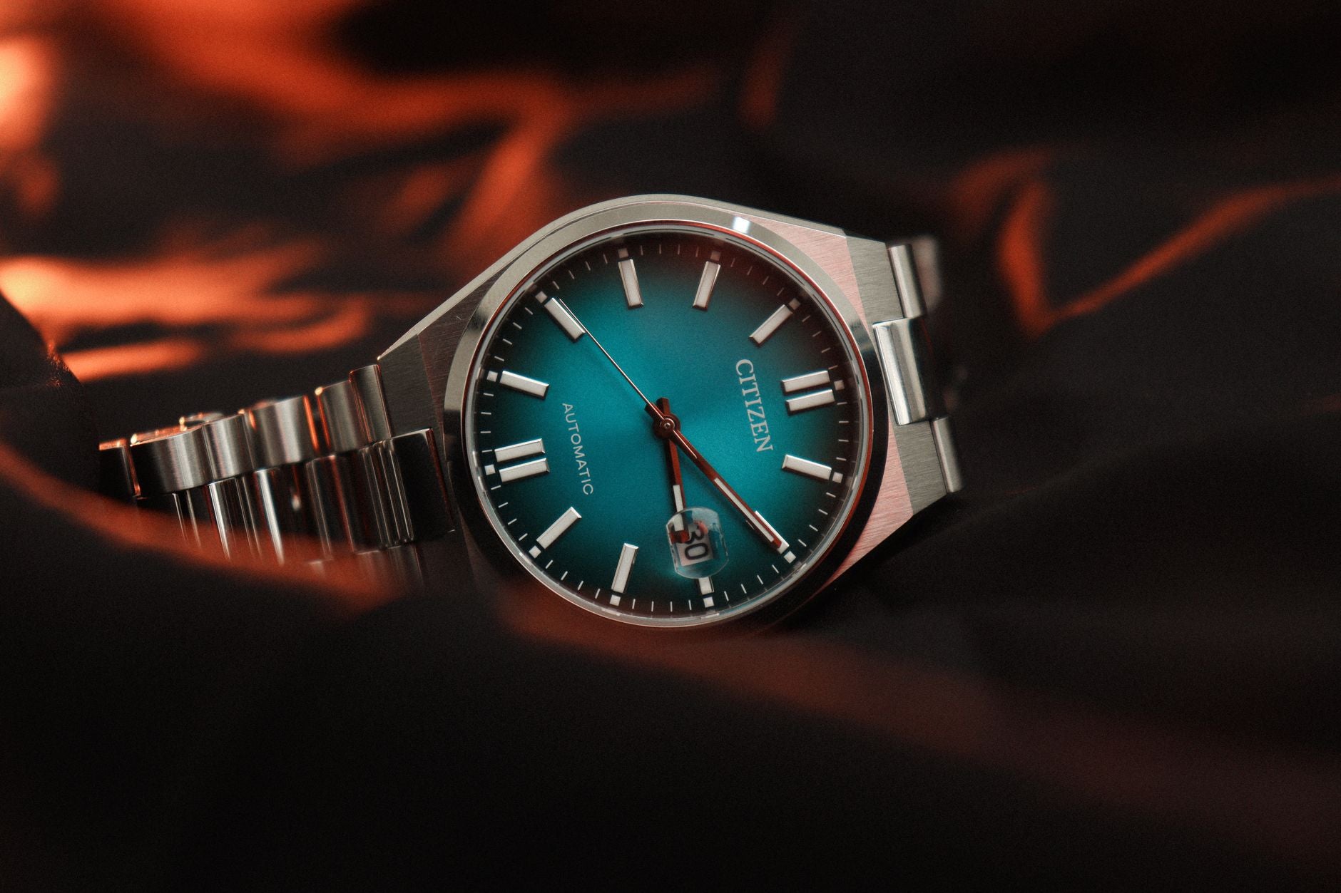 Stylish Citizen wrist watch featuring a teal dial, captured in artistic studio lighting.