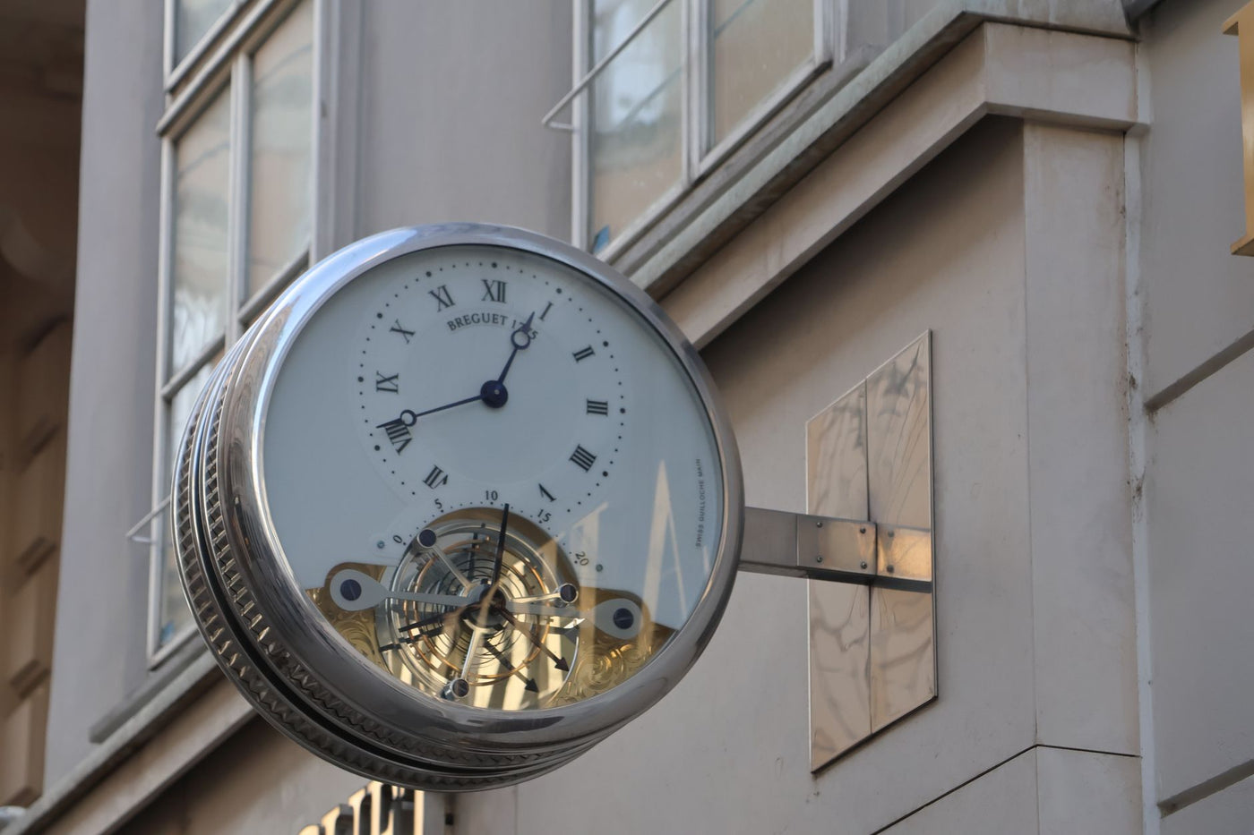 Classic street clock with Roman numerals on urban building facade.