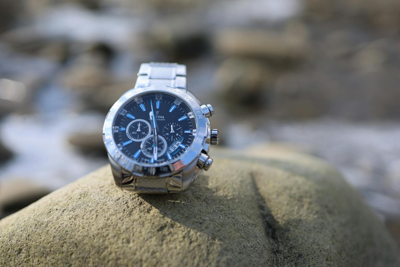 Elegant luxury watch displayed on a large rock in an outdoor setting.