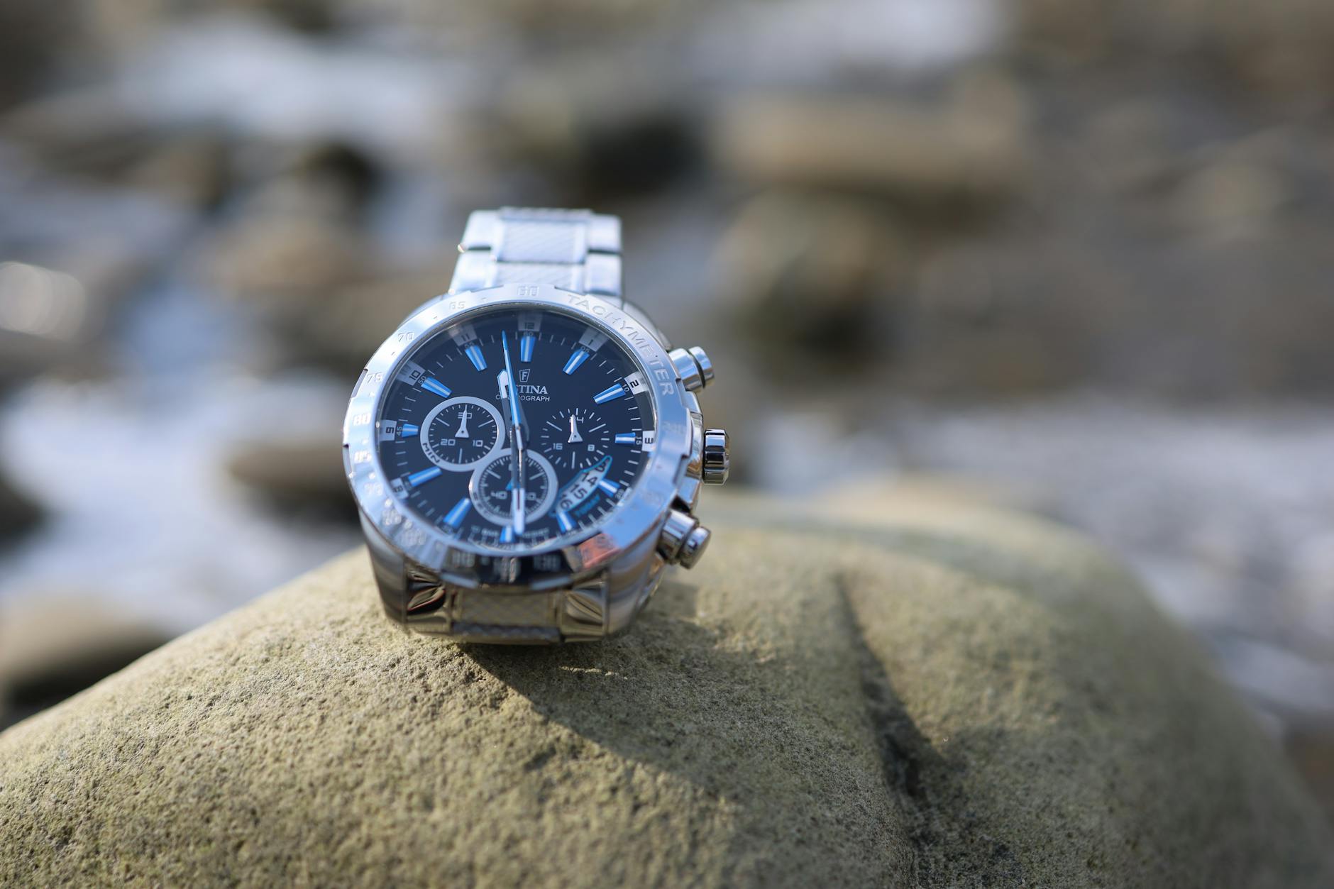 Elegant luxury watch displayed on a large rock in an outdoor setting.