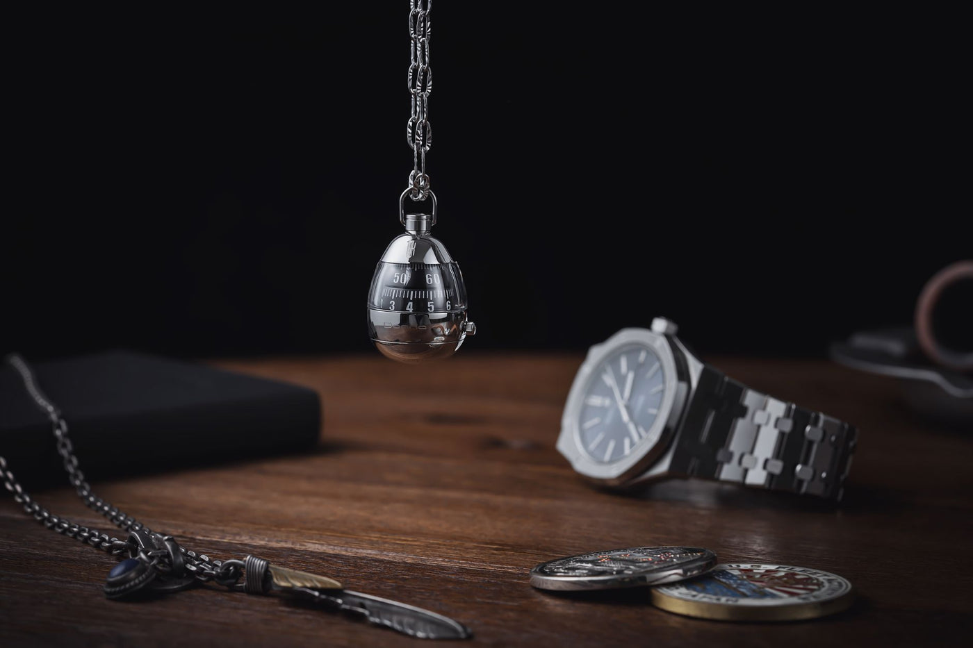 A sophisticated arrangement featuring a silver wristwatch, chains, and a metal timer on a wooden table.