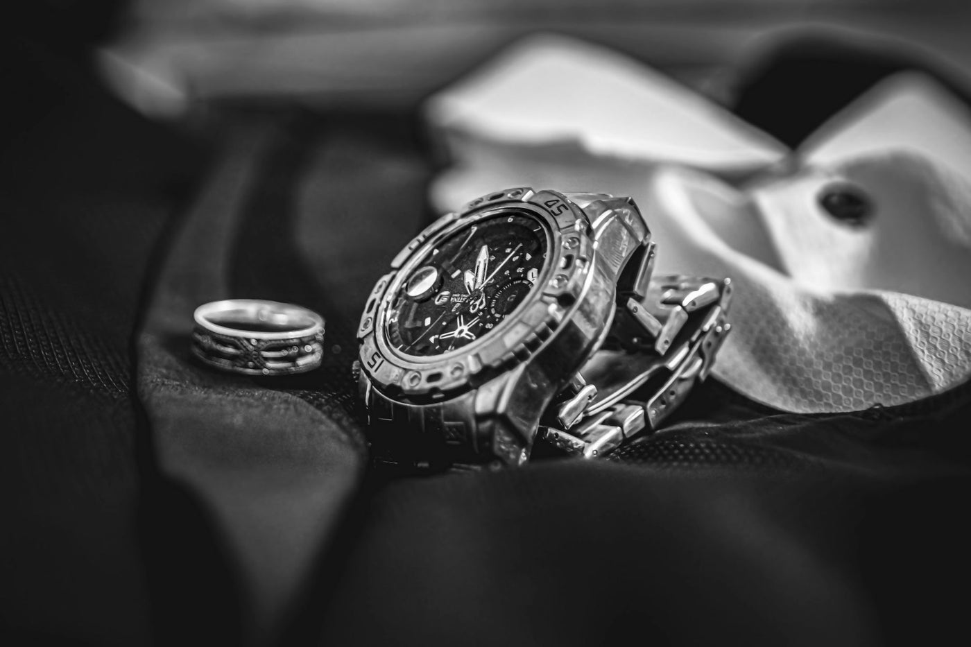 Stylish black and white close-up of a wristwatch and ring, perfect for fashion or luxury themes.