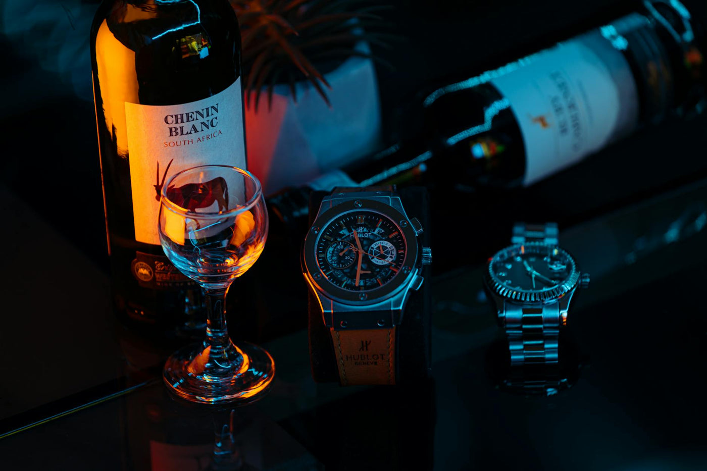 Elegant arrangement of wine and wristwatches with artistic lighting.