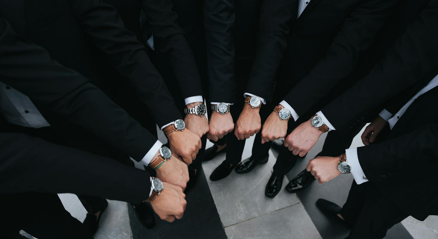Group of executives showing luxury wristwatches in unity gesture.