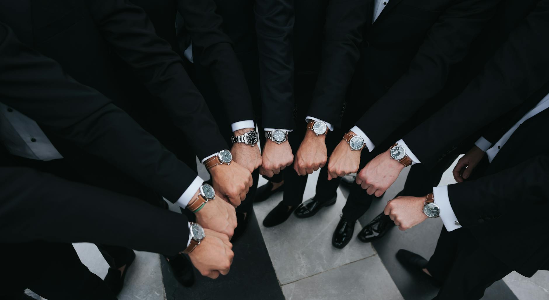 Group of executives showing luxury wristwatches in unity gesture.