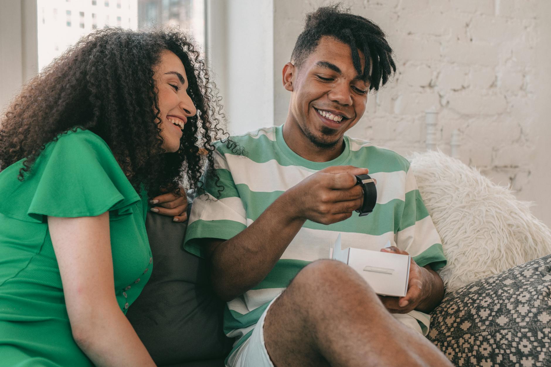 A cheerful couple enjoys a moment of happiness as they open a gift together indoors.
