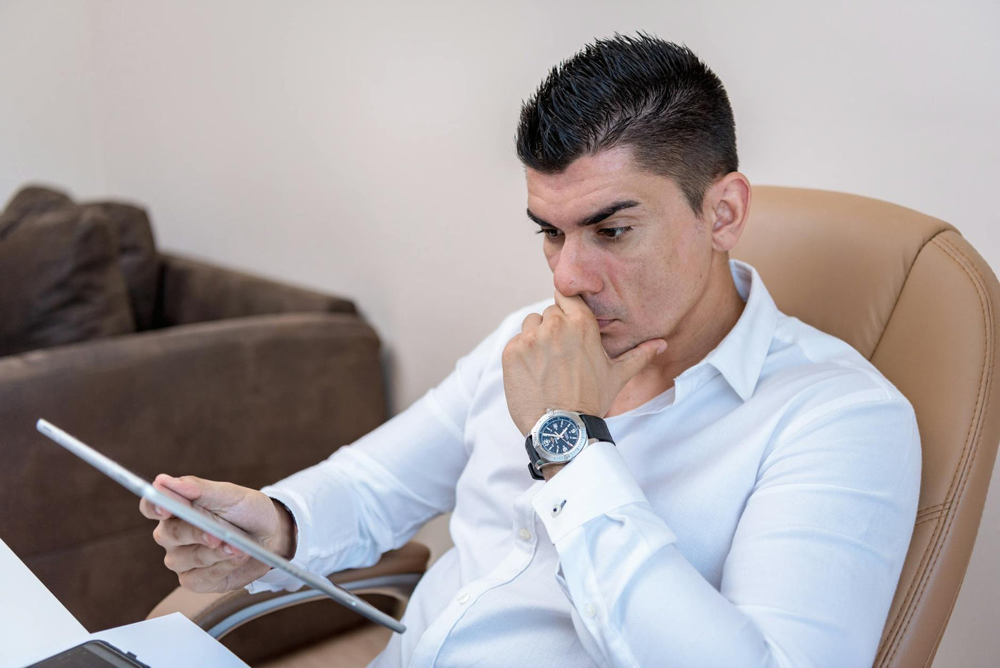 Man in white shirt intently using a tablet in a contemporary office setting.