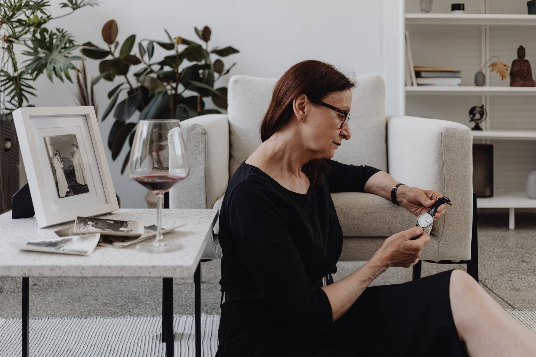 Elderly woman in a contemplative moment indoors, surrounded by memories.