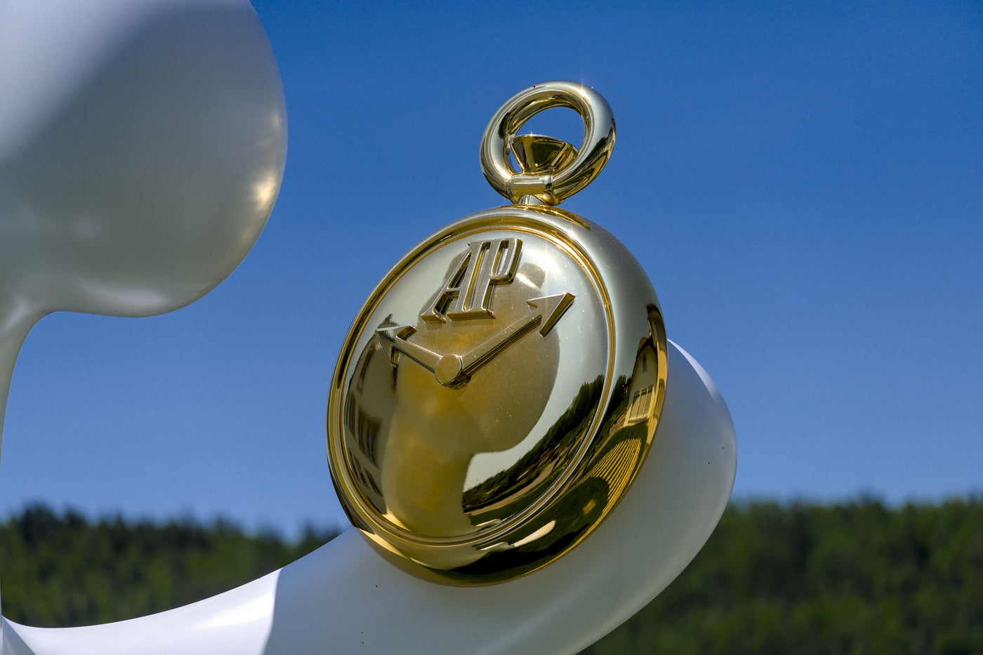 Close-up of a golden pocket watch set against a sunny blue sky, reflecting artistic elegance.