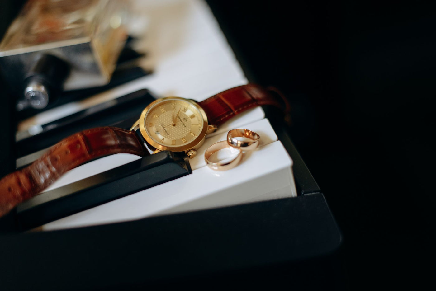 Close-up of a classic watch with gold rings on piano keys, symbolizing elegance and timeless beauty.