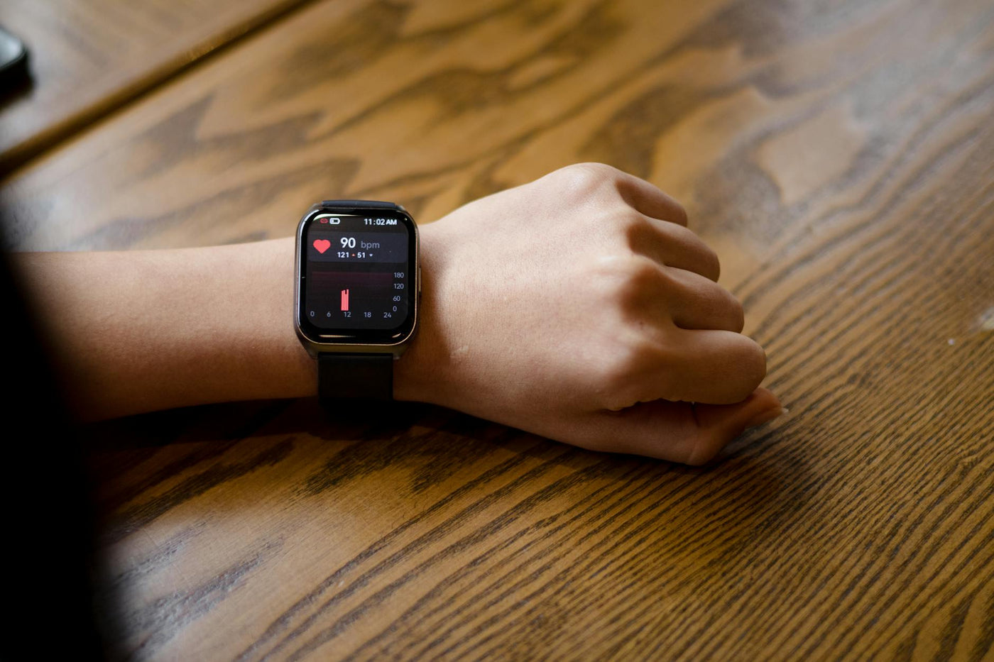Close-up of a smartwatch displaying a heart rate of 90 bpm on a person's wrist.